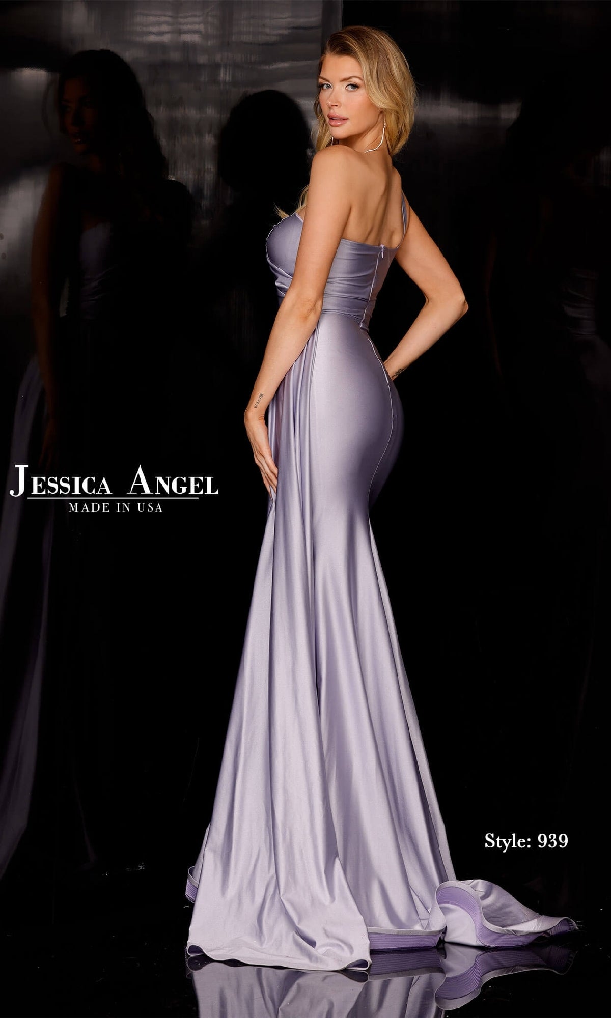 A woman poses sideways in a fitted, floor-length lavender Side-Drape Long Prom Dress by Jessica Angel (Style 939), featuring satin fabric, a mermaid skirt, and a one-shoulder design. Black background with